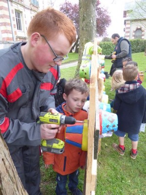 Fixation d'un nichoir par un jeune de l'IME de la Fresnelière devant l'oeil attentif d'un grand de la maternelle.