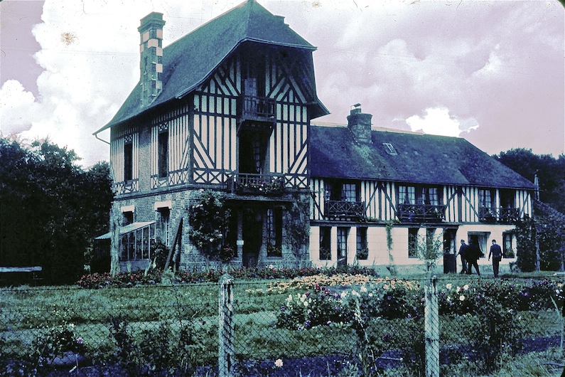 La ferme du Gros chêne où est encore à cette date, entreposée la collection de R. Brun. Sur la photo, il est le premier à entrer dans la maison. La pièce où sont exposés fossiles, oiseaux, mammifères, herbiers, etc. est située à gauche de l'entrée (une porte entre deux fenêtres). Son laboratoire est à droite de la porte d'entrée (large fenêtre).<br />Diapositive J. Alamargot, 22 août 1965 (recolorisée, couleurs virées)