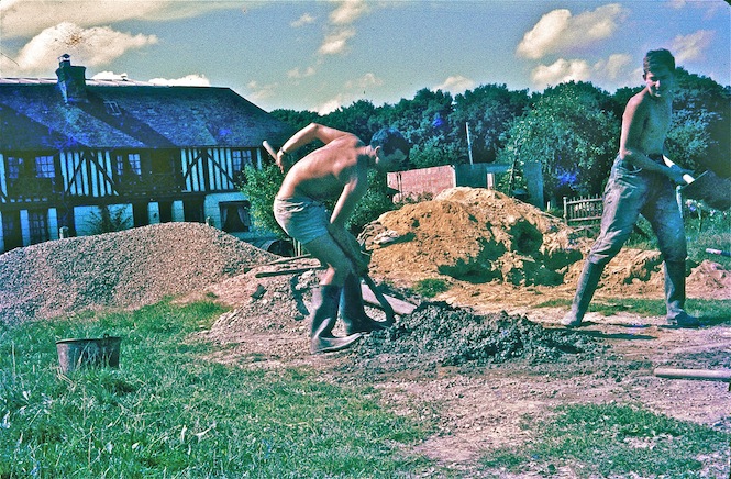 Jacques Alamargot (au centre de la photo) gâche du béton destiné à la construction du musée de Friardel où seront présentées les collections naturalistes de Roger Brun. Le bâtiment en construction est visible à l'arrière plan au centre du cliché. Ce nouveau musée était censé protéger les collections du feu et de l'humidité, ce qui s'avéra faux pour ce dernier risque après le décès de R. Brun. Les collections finirent par être transférées au musée du Havre.<br />2à août 1965<br />Cliché collection J. Alamargot confié à J Collette;  Tirepied le 22 mai 2012.