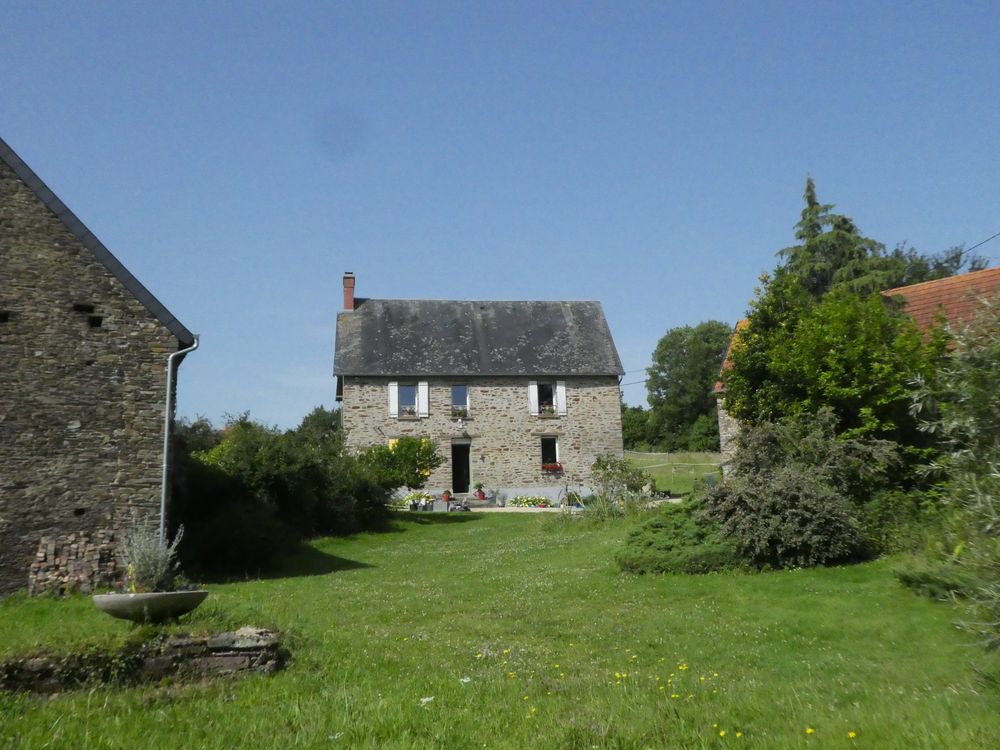 La maison d'habitation et le jardin à l'avant , très boisé avec arbres d'ornement, arbustes et buissons. Le bâtiment à droite accueille au moins deux couples d'hirondelle rustique. La pelouse est plutôt une prairie.