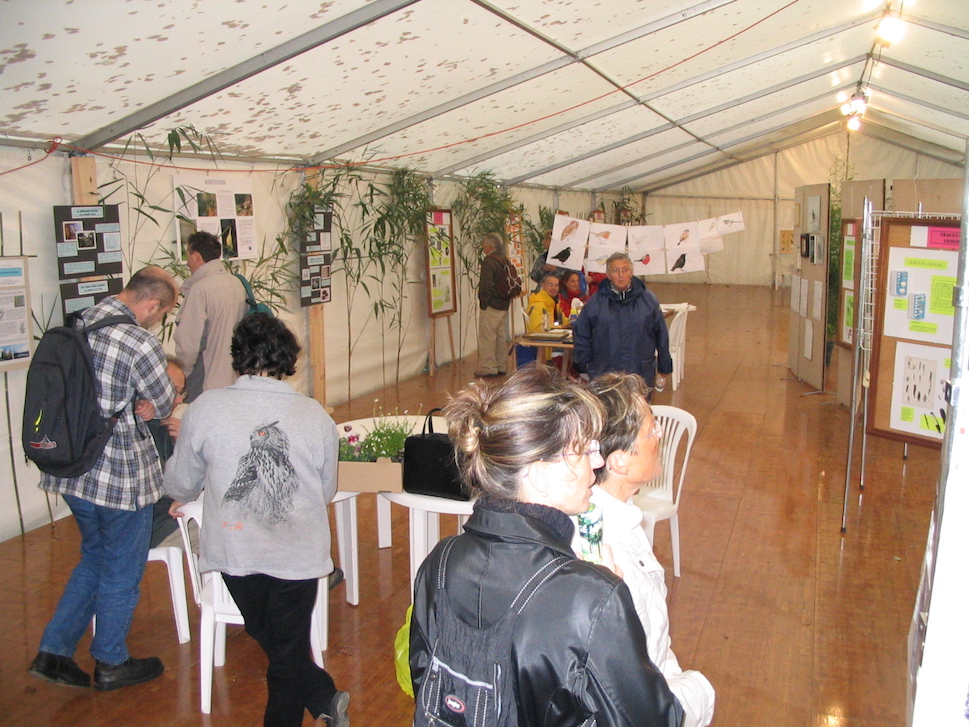 Fontaine-Henry - Jardins et oiseaux - L'installation du stand mobilisa plusieurs adhérents (Claude Lebouteiller, Nicole et Jean Collette, désolé pour les autres, mes notes sont muettes sur le sujet..) Le partage de l'espace sous la tente fut l'occasion d'un petit conflit avec les représentants de la LPO voisine qui souhaitaient "mélanger" les panneaux avec les nôtres. Entre mes panneaux bricolés mais appétants et les dépliants tout prêts de la LPO, je ne souhaitais pas qu'il y ait de confusion entre les deux structures.<br />De dos au premier plan à gauche, François Gabillard, qui m'aida de nombreuses fois à monter les plaquettes des animations concertées de printemps; à côté, de dos, Céline Chartier. Yves Grall est au fond à gauche devant un panneau; au fond, en rouge et jaune, Guillaume Debout et sa femme Karine qui tenaient un atelier dessin.