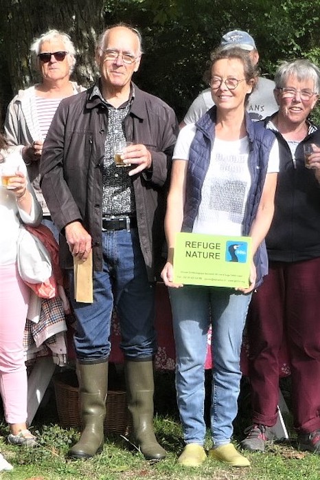 Alain Aupoix à G, Nathalie Hédin portant la pancarte; cidre du Pays d'Auge et local puis tartes et desserts maison. Le refuge ne nourrit pas que les oiseaux!
