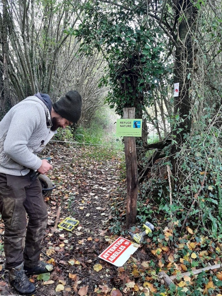 Maxime installe la pancarte à l'entrée du chemin.